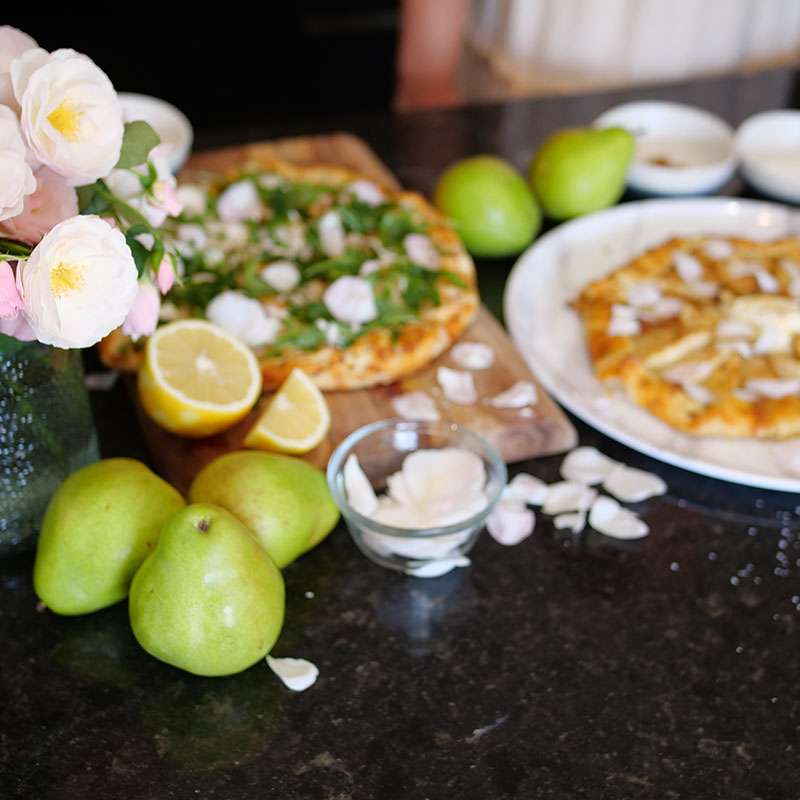 A vase of Flavorette edible roses next to food that has been garnished with rose petals